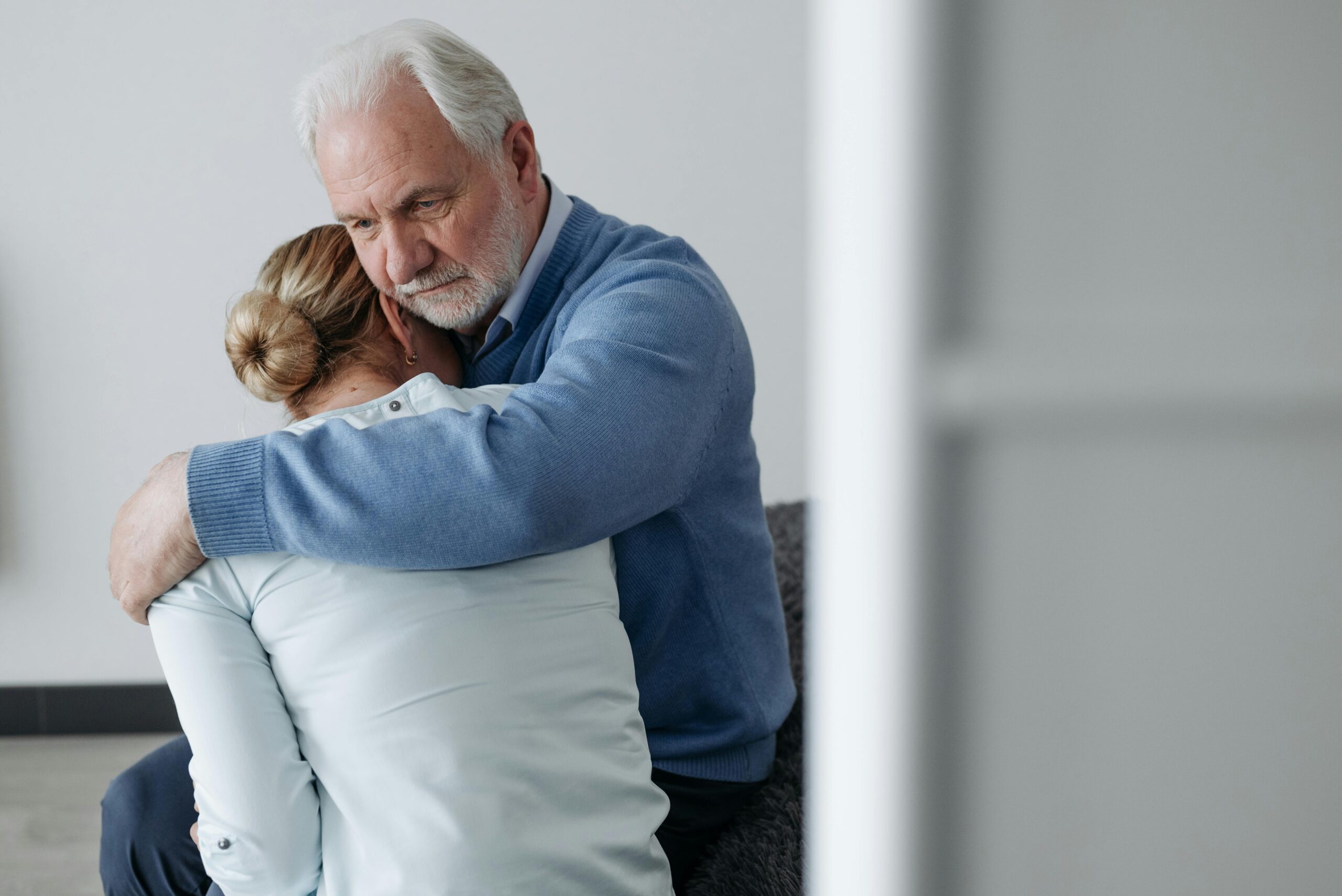 A senior man consoles a woman in a moment of grief, offering comfort and support.