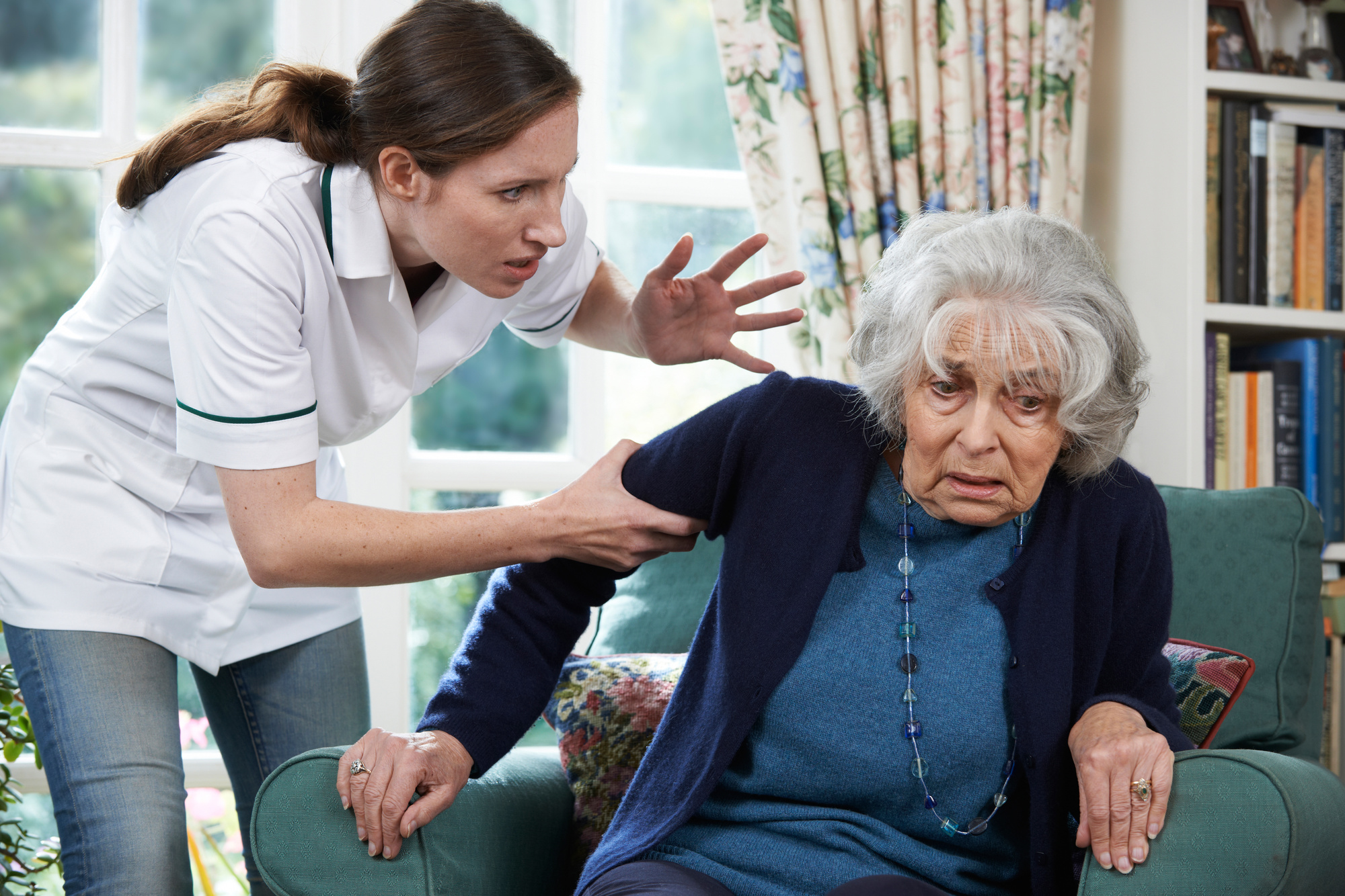 A distressed elderly woman being aggressively handled by a caregiver.