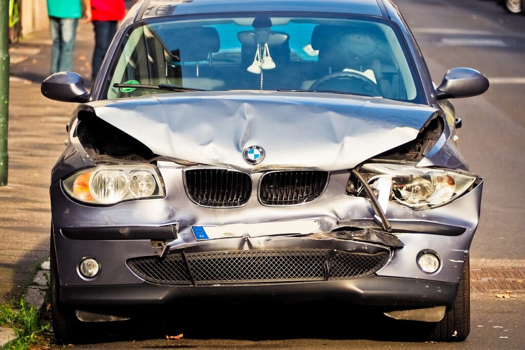 A front view of a damaged BMW car with a crumpled hood after an accident.