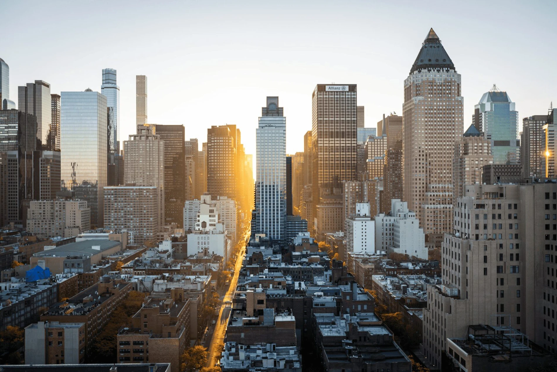 A bright morning view of a city skyline with sunlight streaming through tall buildings.